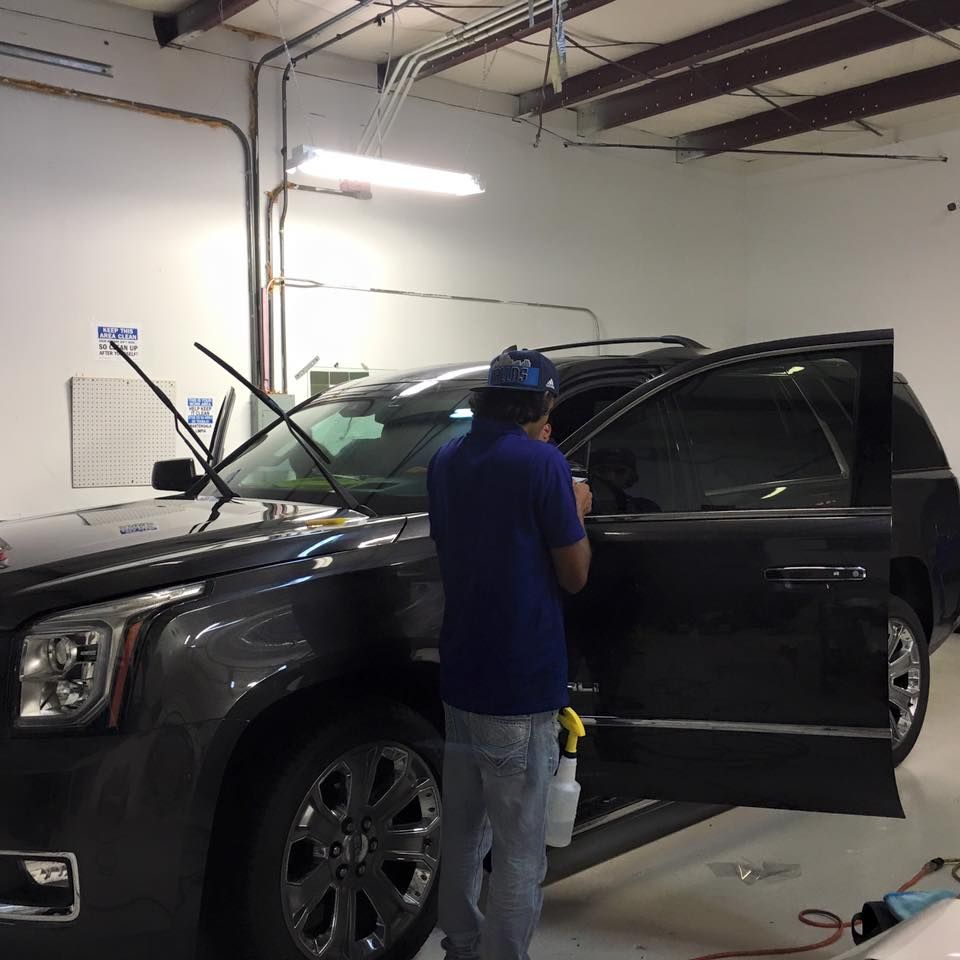 a man in a blue shirt is working on a car