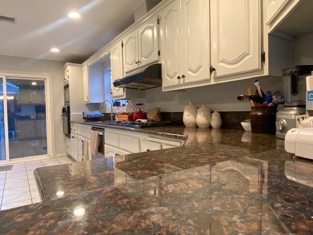 Bright kitchen with white cabinets, stainless appliances, and a glossy marble countertop