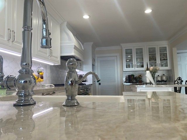 Modern kitchen with marble island, chrome faucet, and white cabinets in bright natural light