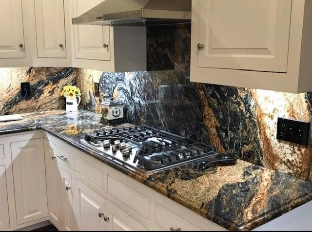 Modern kitchen with white cabinets, marble-look countertops, and a gas cooktop under a range hood