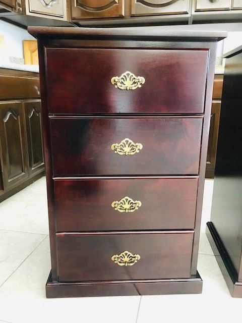 Dark wood four-drawer chest with brass handles in a home interior
