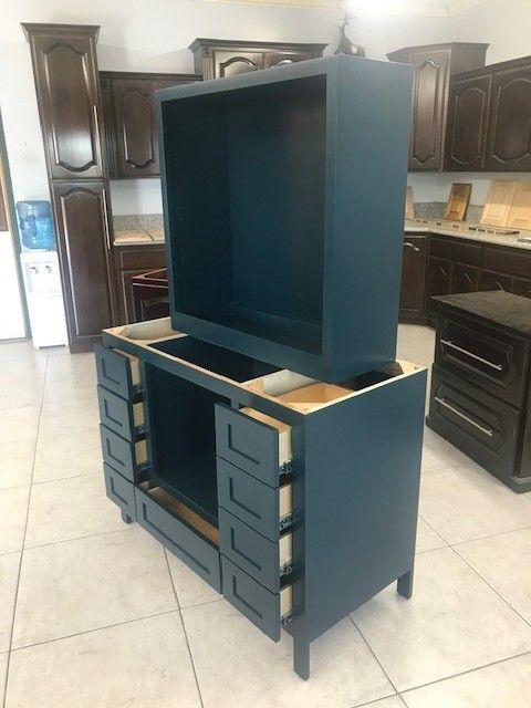 Dark blue TV cabinet with drawers and a large top compartment in a kitchen showroom