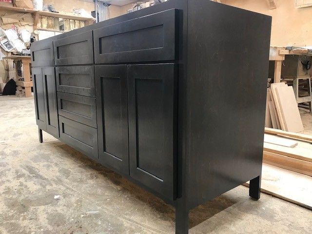 Black wood kitchen cabinet with drawers and doors in a workshop