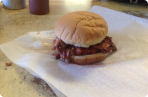 Barbecue sandwich on a bun, resting on a paper towel.