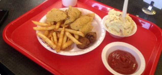 A red tray with a plate of fried food, fries, coleslaw, and ketchup.