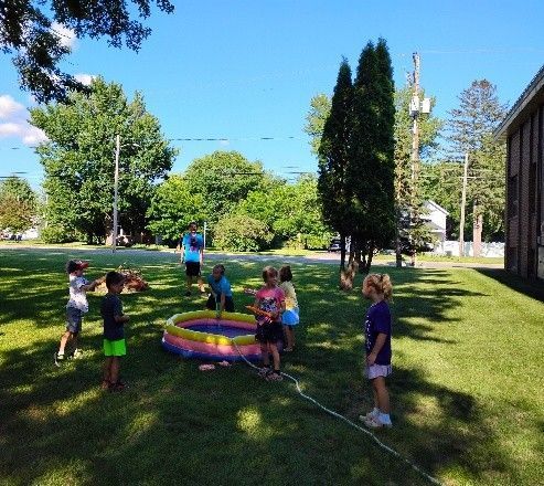 Children playing on a grassy lawn with colorful hoops in a sunny park.