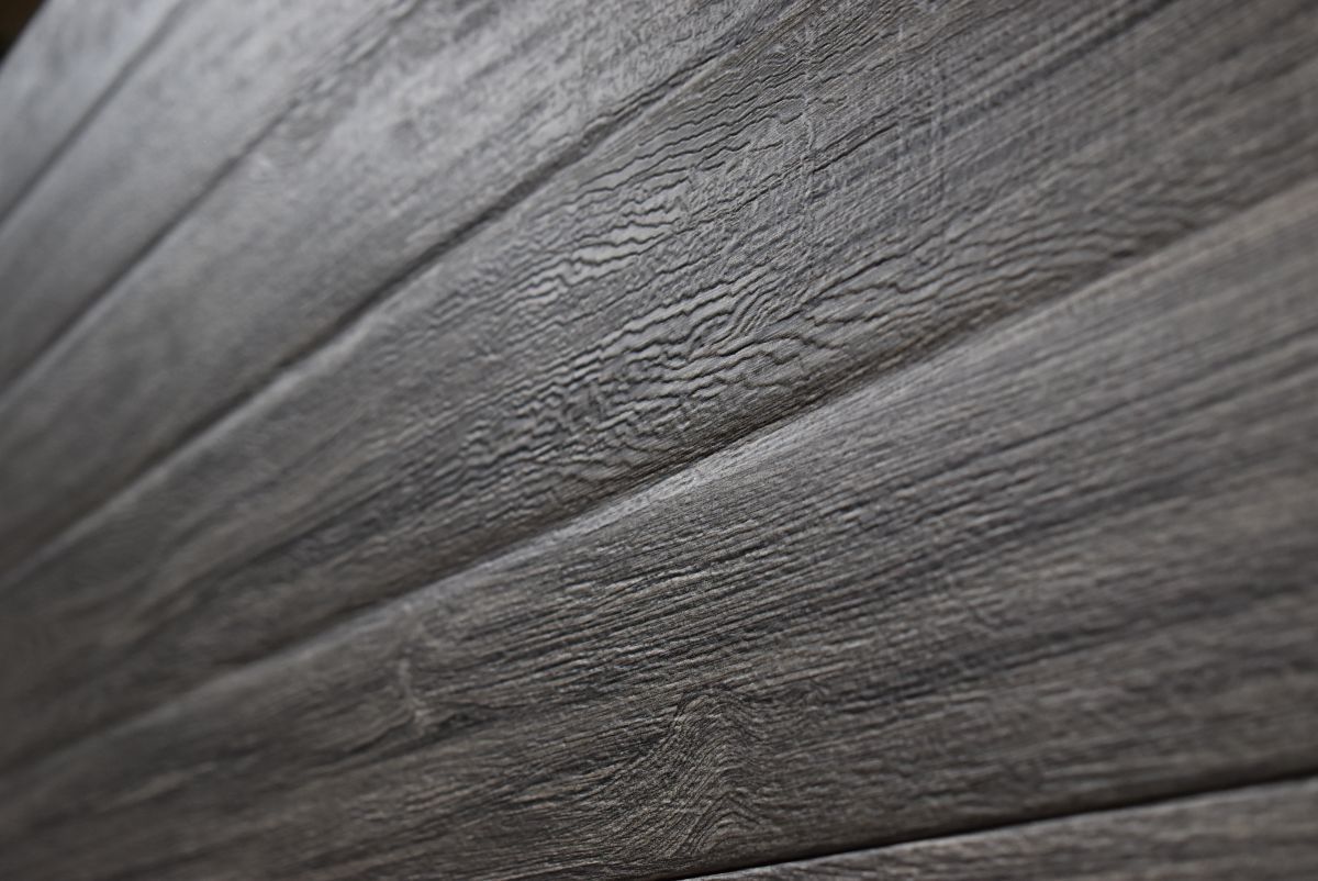 Close-up of weathered, dark gray wooden planks with visible grain and texture.