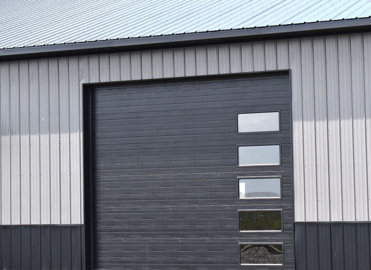 Black and gray building with a garage door that has 4 rectangular windows.