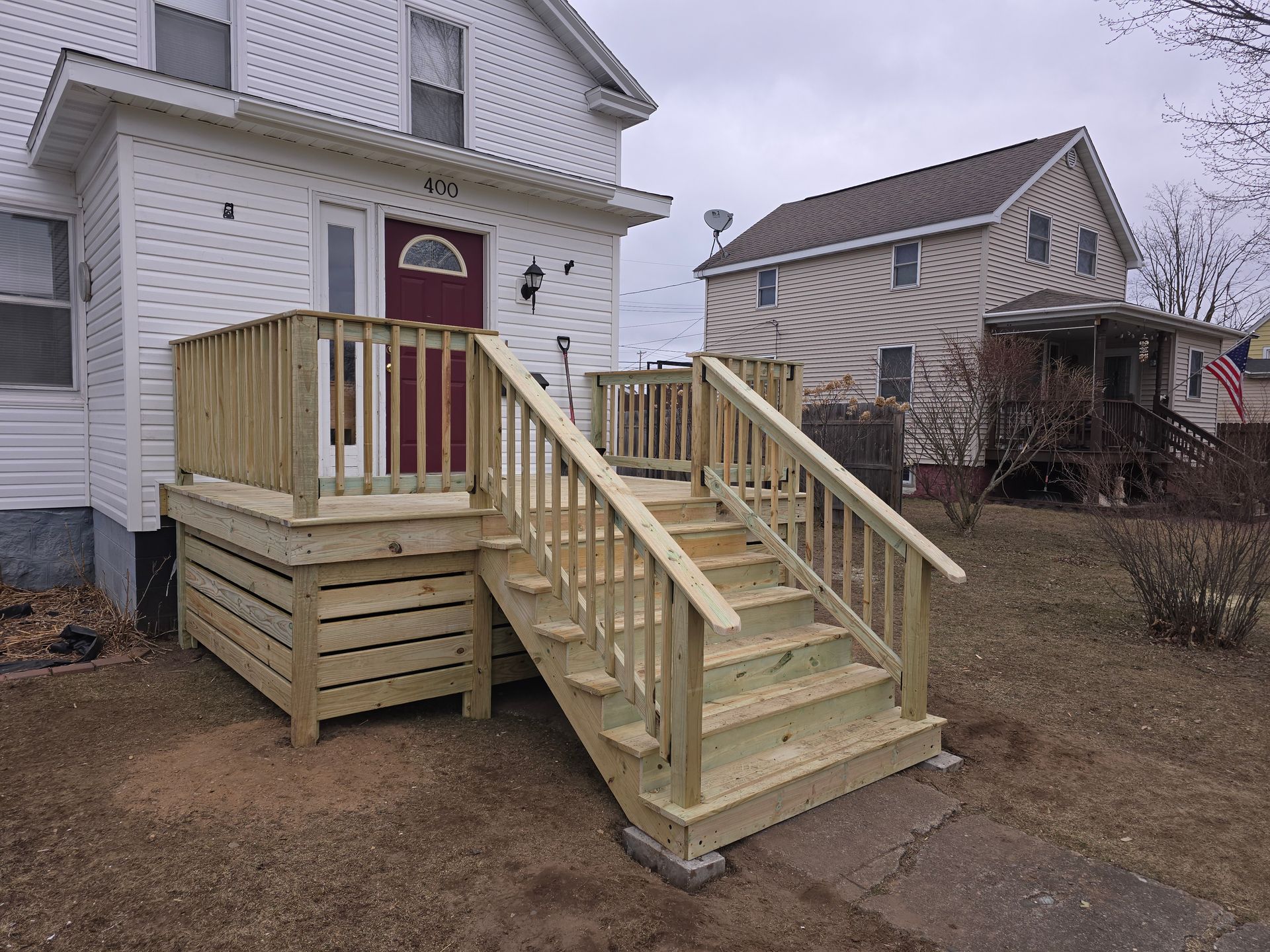A white house with a wooden deck and stairs