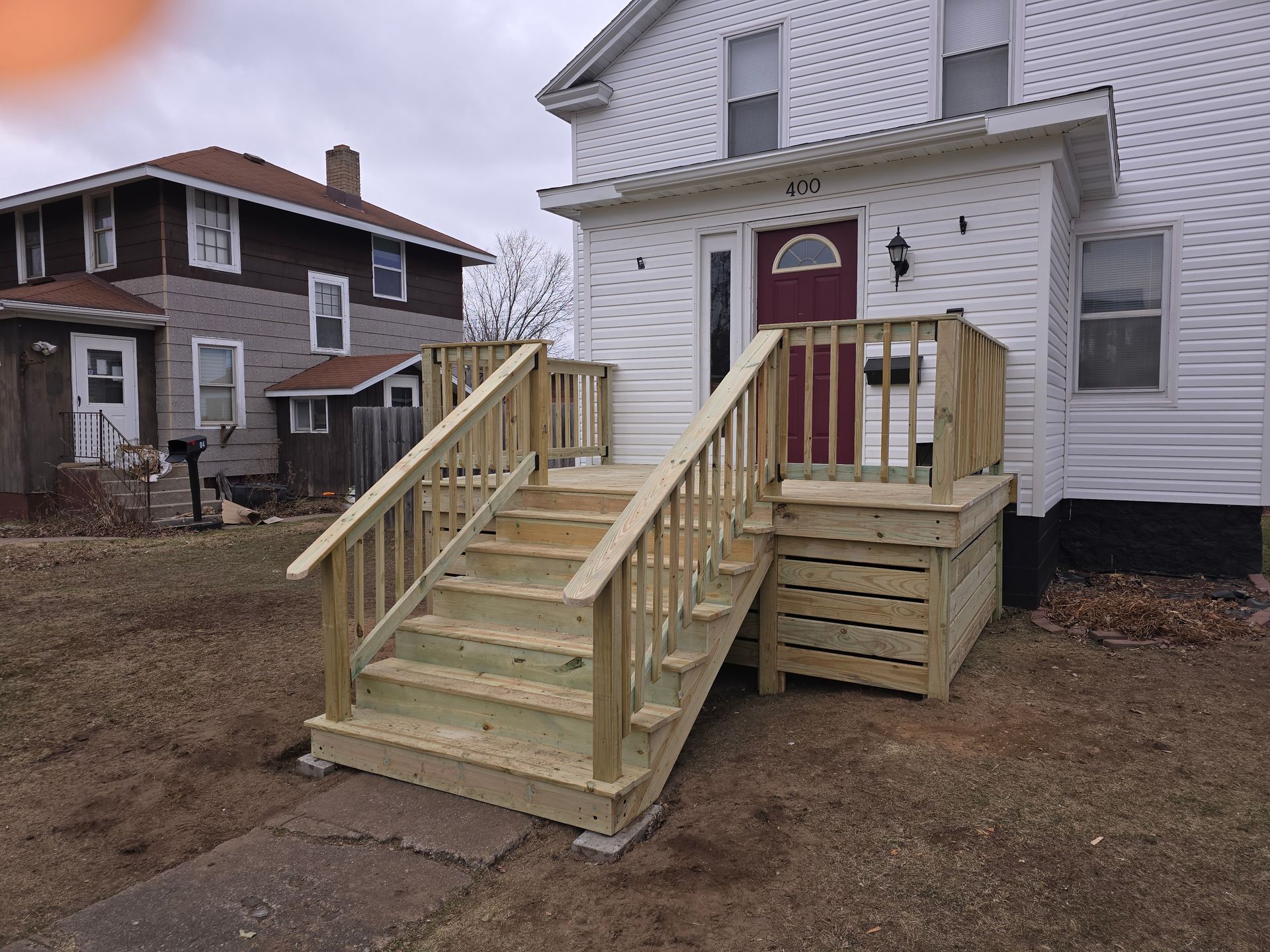 A white house with a wooden deck and stairs