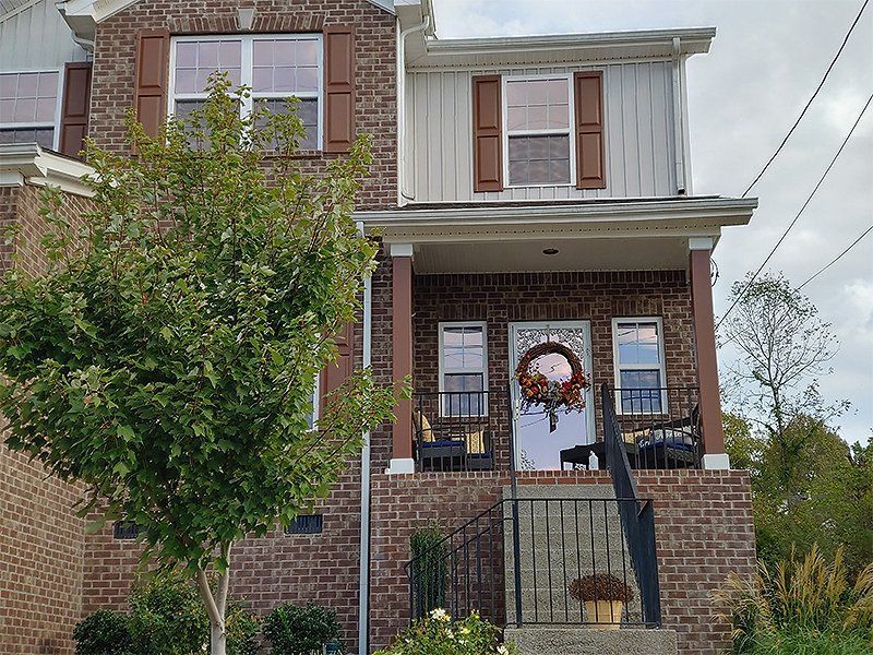 Two-story brick house with brown trim and a decorated wreath on the door.
