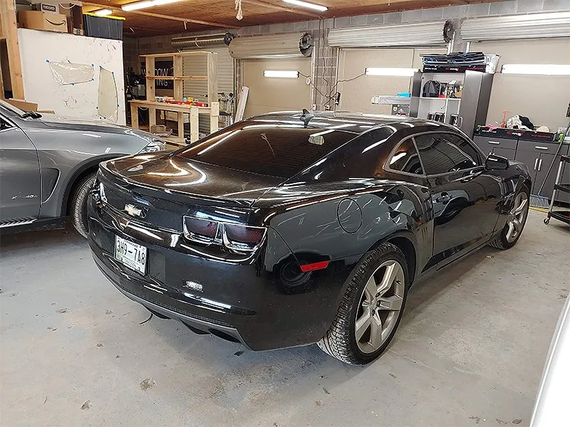 Black Chevrolet Camaro in a garage, angled view.