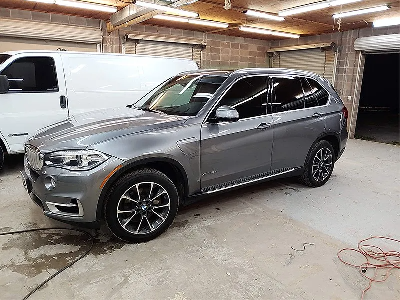 Gray BMW SUV inside a garage; white van is partially visible in the background.