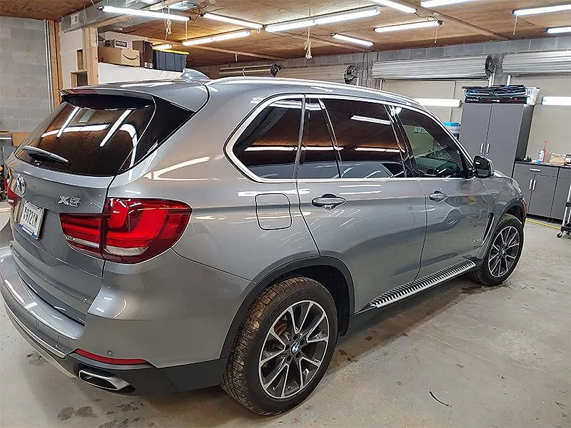Gray BMW SUV with tinted windows parked inside a garage.