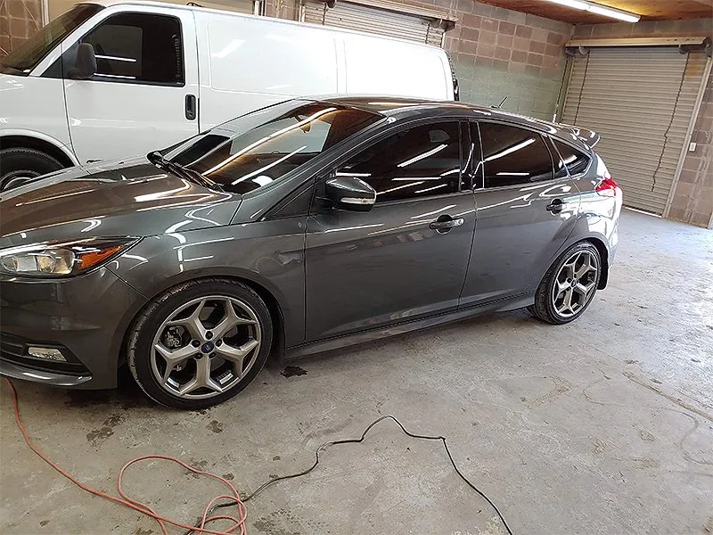 Gray Ford Focus parked inside a garage, next to a white van.