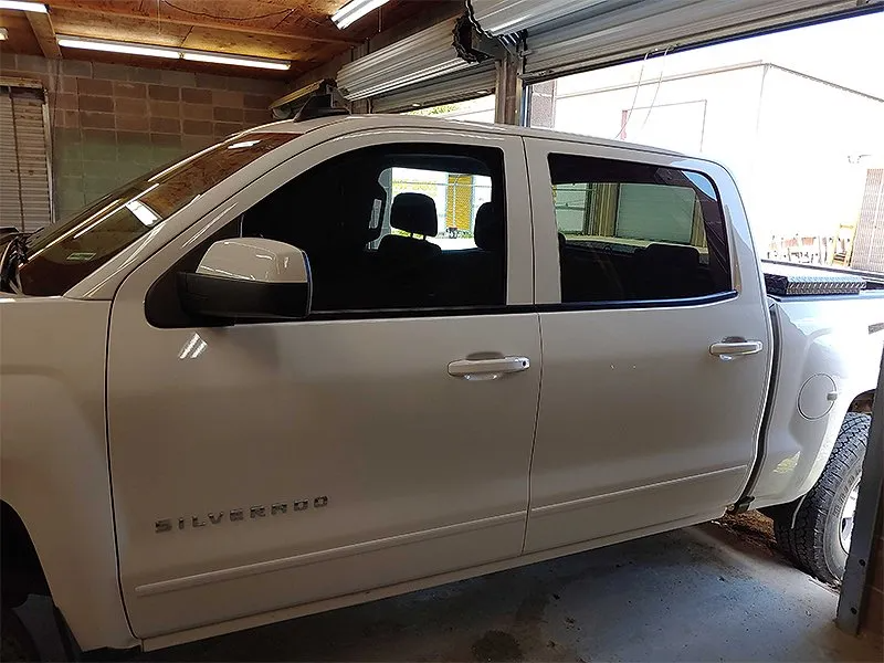 White Chevy Silverado pickup truck in a garage with tinted windows.