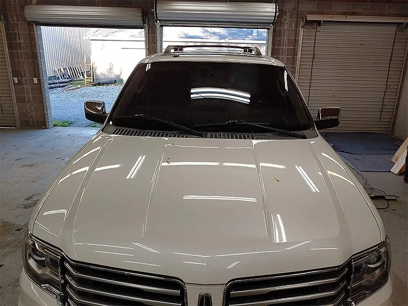 White Lincoln Navigator SUV parked inside a garage with tinted windows.