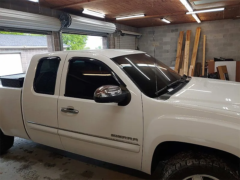 White GMC Sierra truck inside a garage with a partially open door.
