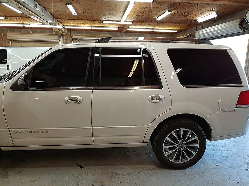 White Lincoln Navigator with tinted windows parked in a garage.