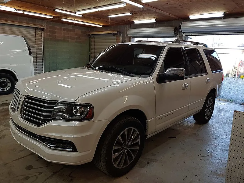 White Lincoln Navigator SUV parked in a garage with tinted windows.