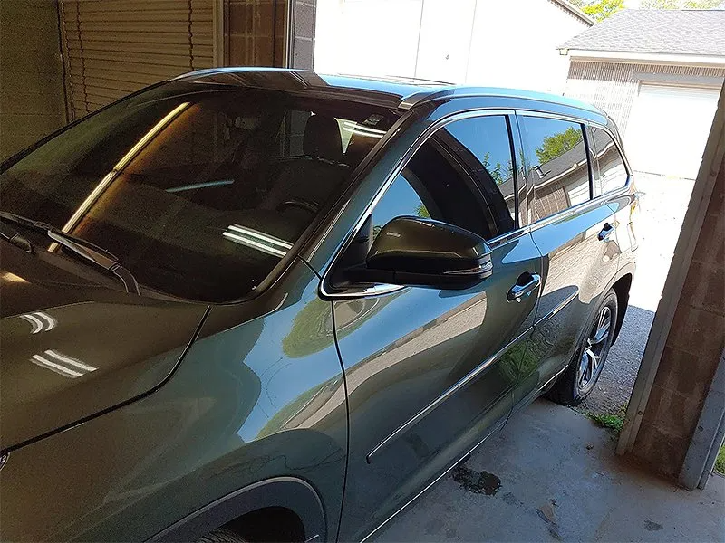 Green SUV parked under a covered area, windows tinted.