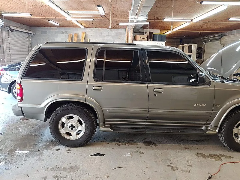 Silver SUV with tinted windows parked inside a garage, hood open.