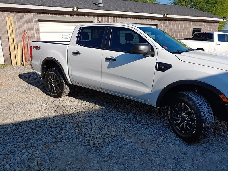 White Ford Ranger pickup truck parked on gravel.