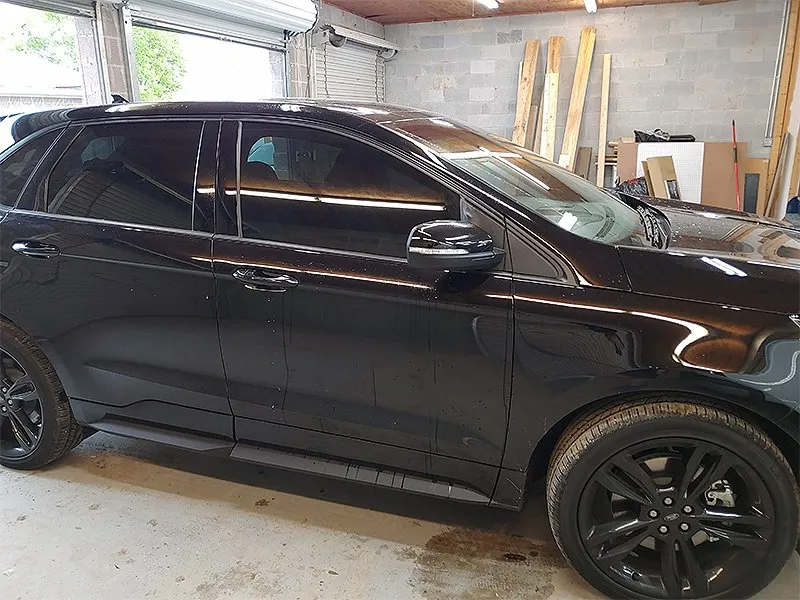 Black Ford Edge SUV with tinted windows parked in a garage.