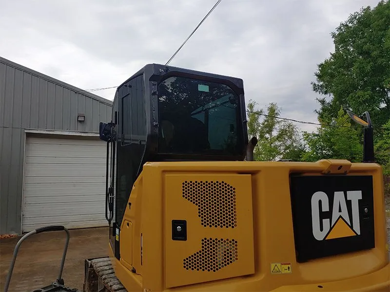 Yellow Caterpillar excavator with black cab against a cloudy sky.