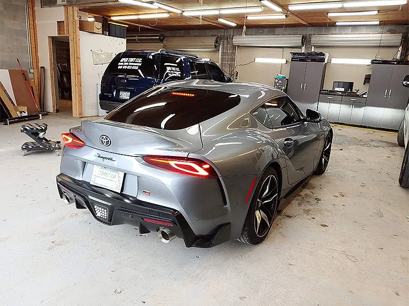 Silver Toyota Supra in a garage, rear view. Tinted windows, black accents, and a clean setting.