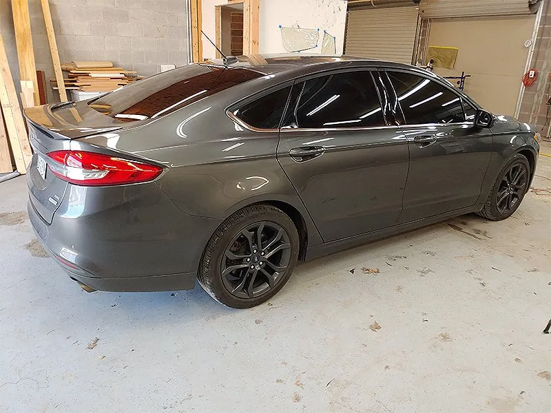 Dark gray sedan with tinted windows parked inside a garage, wheels matching body color.
