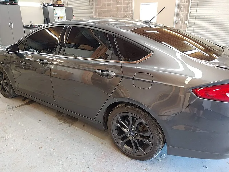 Grey sedan with tinted windows, parked inside a garage.
