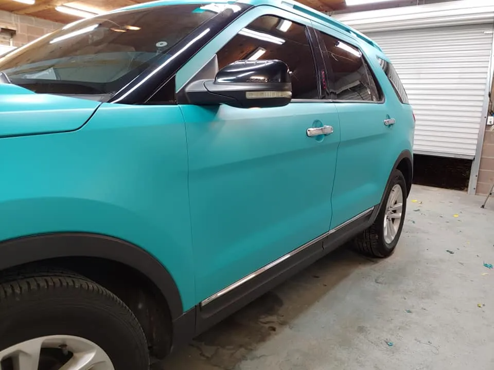 Teal SUV parked inside a garage, showcasing a matte finish wrap.