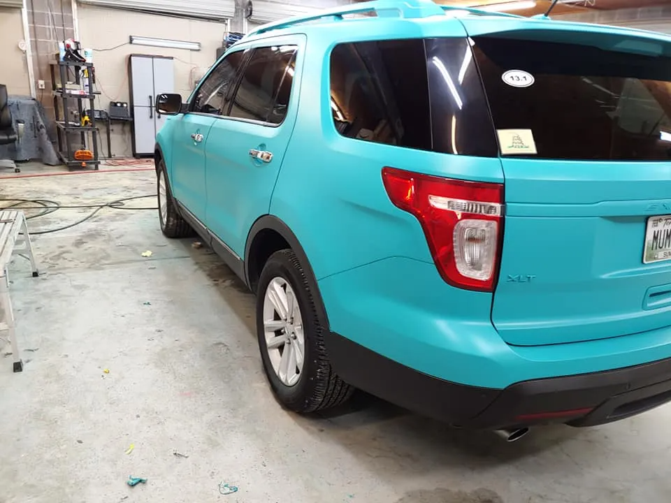 Turquoise SUV parked inside a garage, with black trim, and black tinted windows.