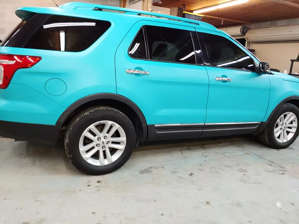 Turquoise Ford Explorer SUV, dark-tinted windows, silver trim, parked indoors.