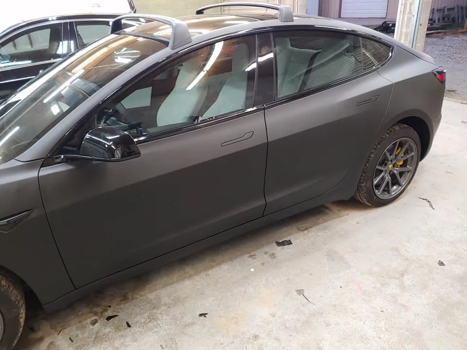Matte gray Tesla car with tinted windows; yellow brake calipers.
