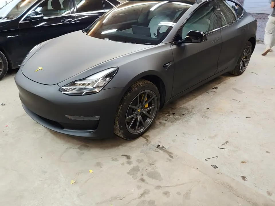 Matte black Tesla in a garage setting.