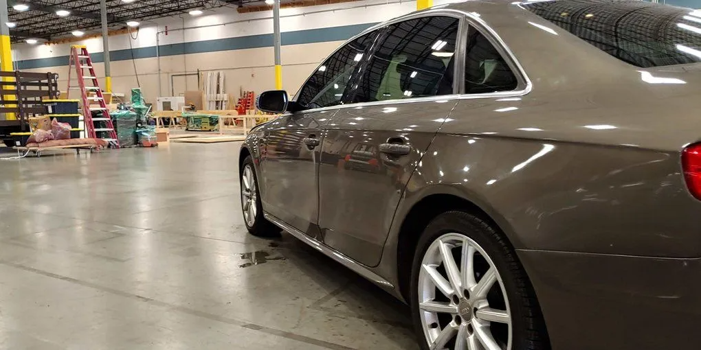 A brown car parked inside an industrial warehouse, side view.