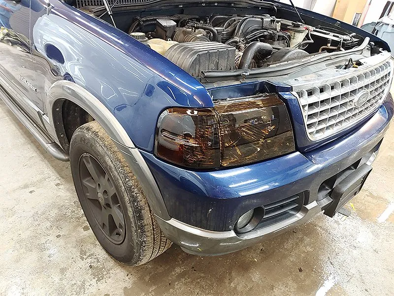 Blue Ford SUV with tinted headlights, open hood, and black wheels.