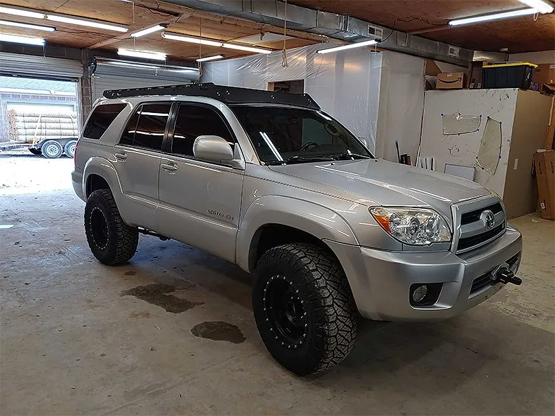Silver Toyota 4Runner with black wheels parked inside a garage.