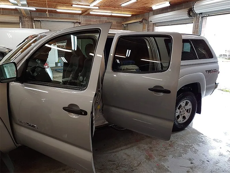 Silver Toyota Tacoma truck with open doors in a garage, showcasing interior and shell.