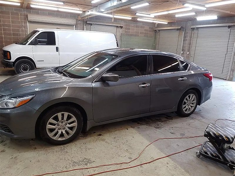 Gray sedan inside a garage, next to a white van.