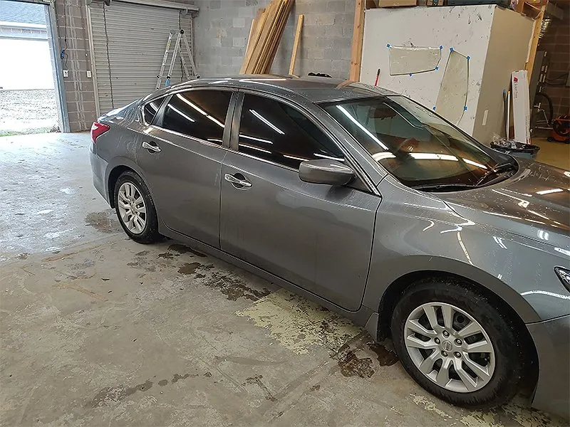 Gray sedan with tinted windows parked in a garage.
