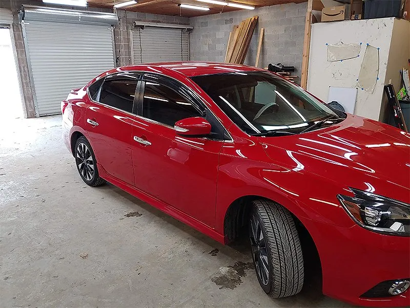 Red Nissan sedan in a garage.
