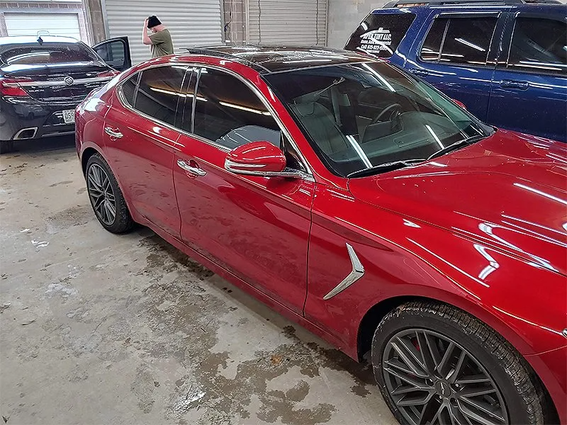Red car with tinted windows, black wheels, in a garage.