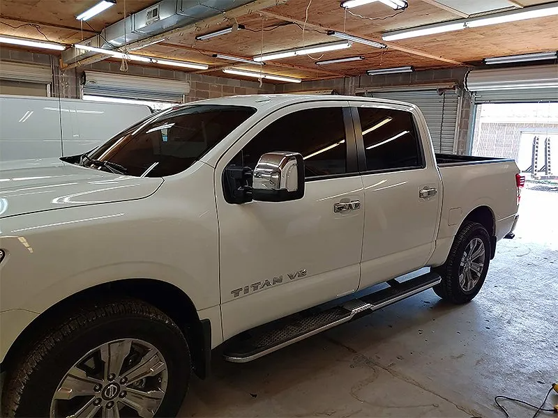 White Nissan Titan pickup truck with tinted windows in a garage.