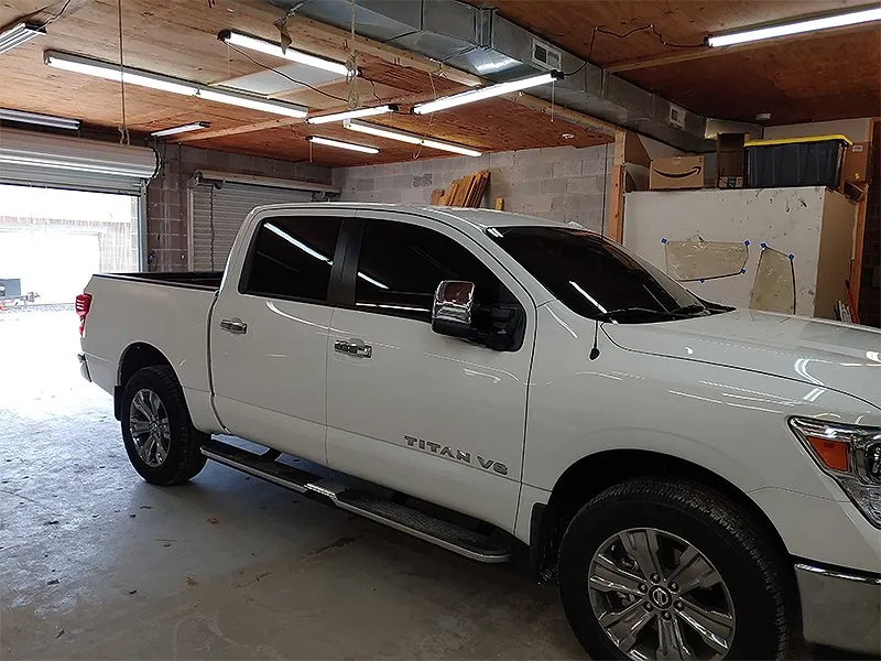 White pickup truck parked inside a garage with the garage door open.