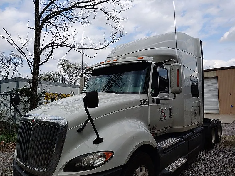 White International semi-truck parked outdoors. Cloudy sky.