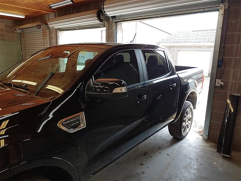 Black pickup truck parked in a garage, facing partially open garage door.