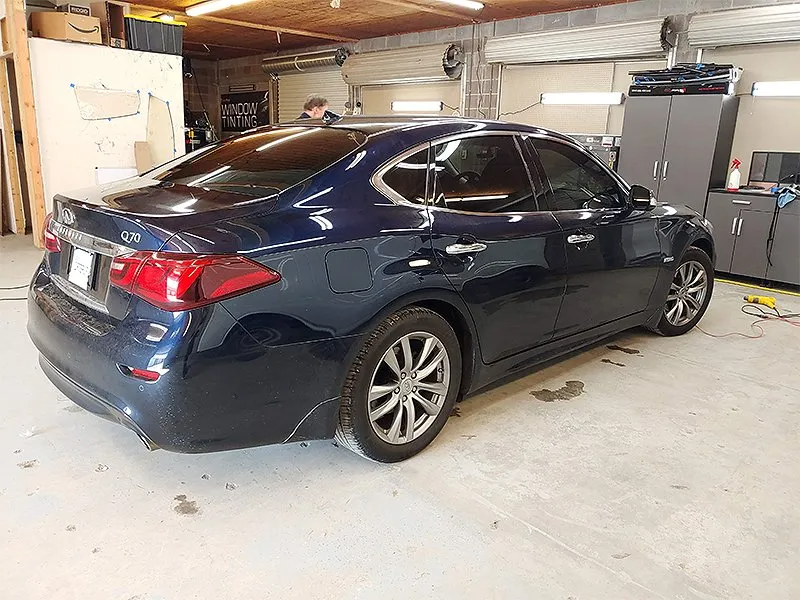 Dark blue sedan with tinted windows in a garage setting.